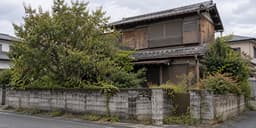 解体を控えた古い木造の空き家と、伸びた庭木やブロック塀が残る敷地