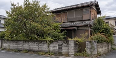 解体を控えた古い木造の空き家と、伸びた庭木やブロック塀が残る敷地